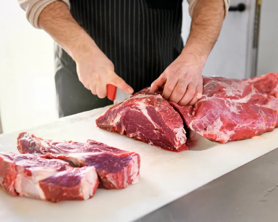 Un carnicero cortando carne fresca de ternera