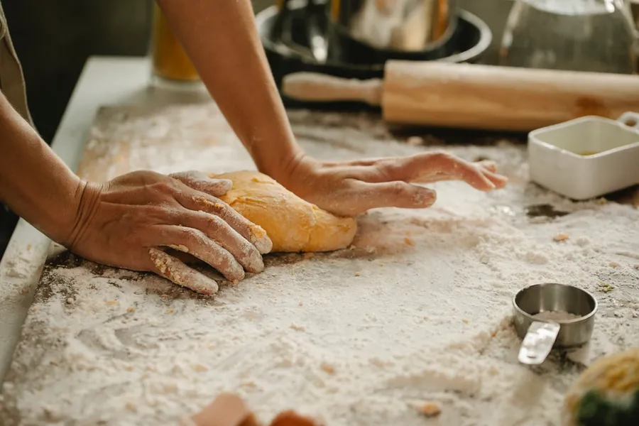 Manos amasando pan artesano sobre la mesa de trabajo